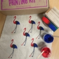 A photo of flamingos screen printed onto a tote bag, includes squeegee and ink tubs